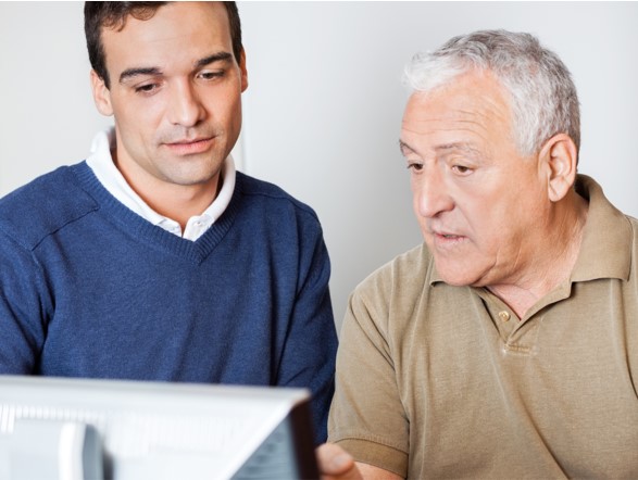 Photo of an older man showing a younger man something on a computer screen