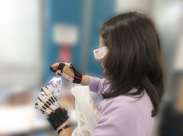 Photograph of someone opening a water bottle while wearing Cambridge simulation gloves and glasses