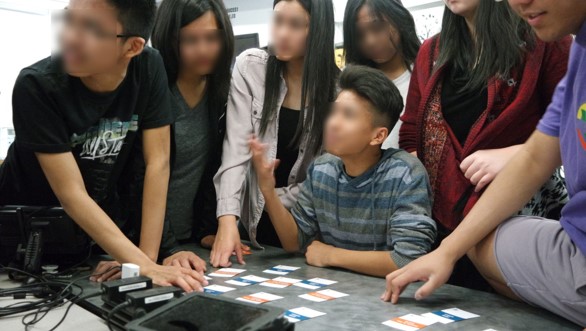 A group of high school students discussing a set of information cards