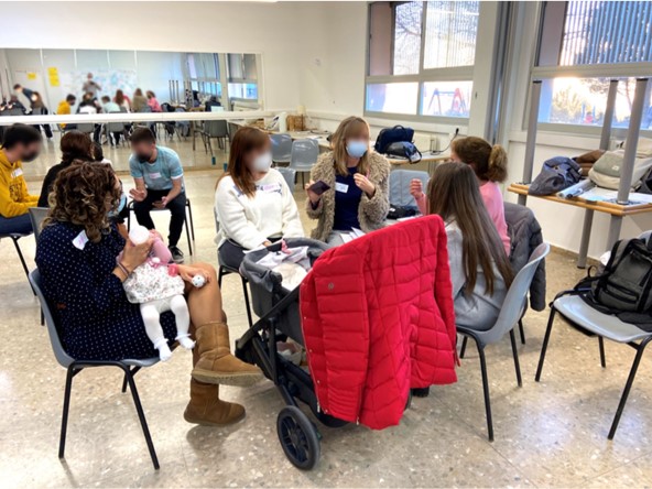 photograph of some participants engaging in discussions within a workshop setting. The participants in the group are female, and one is next to a pushchair and holding a baby