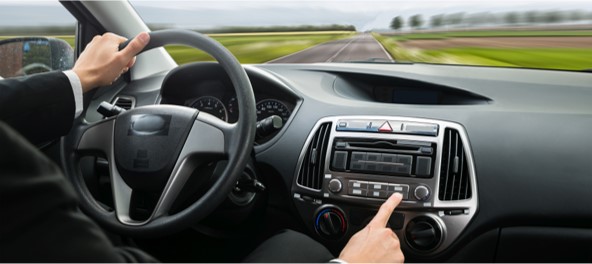 photo of a person driving a car while also trying to control a stereo.
