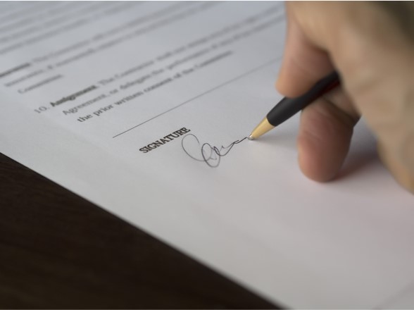 Photo of a hand signing a form.